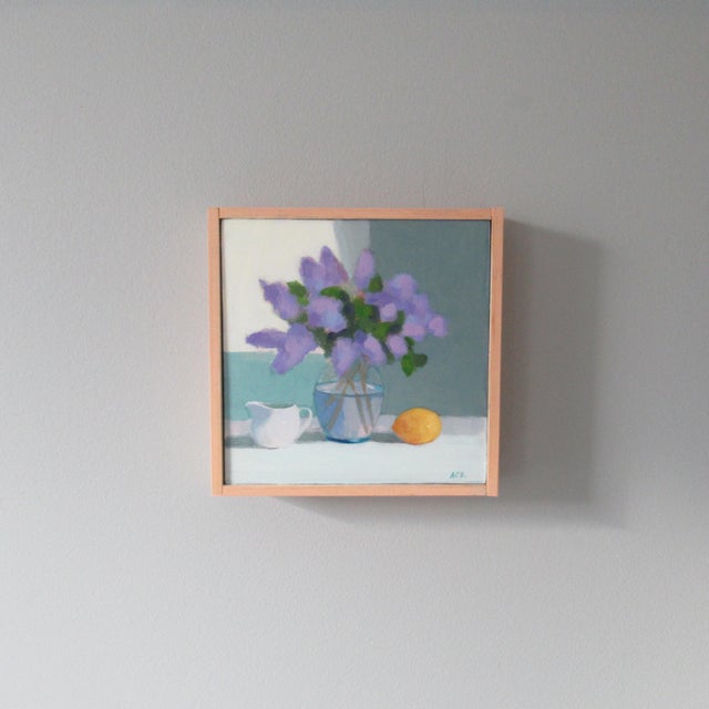 Lilac in a lovely glass vase and the color is set off by a single lemon. It has an impressionistic feel. This painting is...