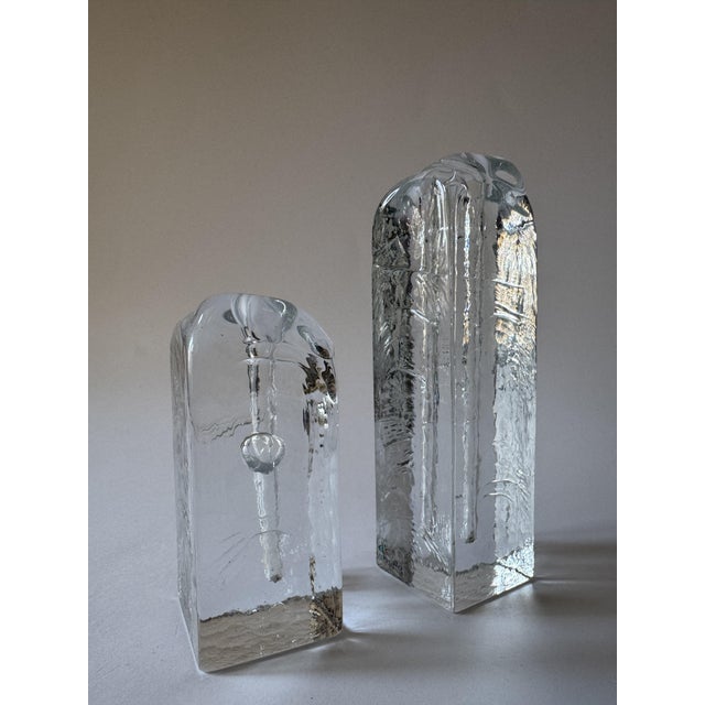 A striking set of two sculptural glass objects produced by Murla, Finland. These solid glass forms resemble frozen...