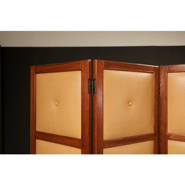 A beautiful four-paneled Brazilian Hardwood folding screen with leather panels on one side and mirrored paneling on the...