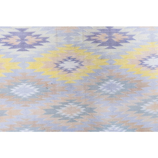This vibrant vintage Indian Dhurrie rug, woven circa 1955, beautifully illustrates the lively geometric aesthetics and...