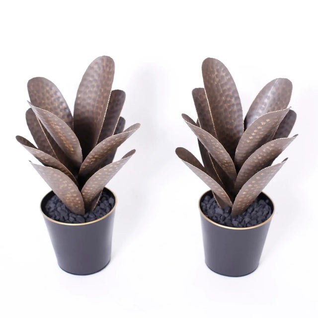 Pair of faux agave plants crafted in brass with a contrived patina and serrated edges set in metal planters with faux...