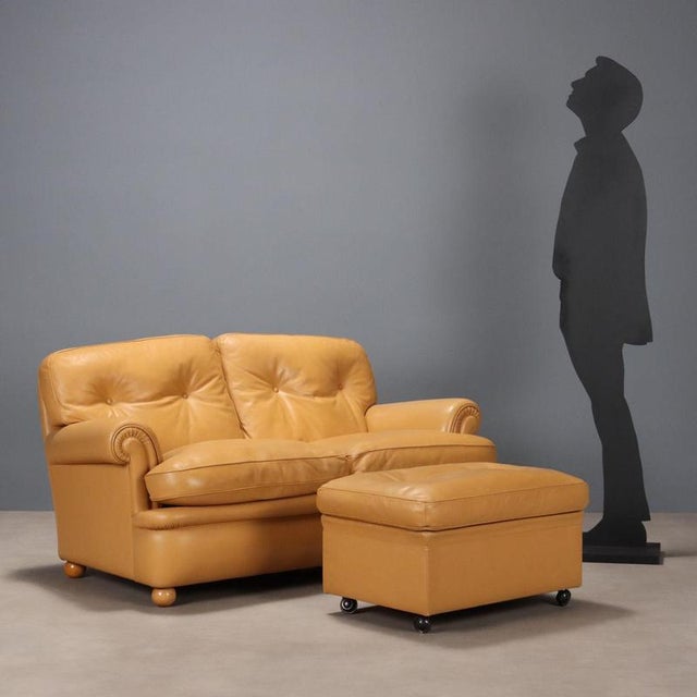 Two-seater sofa with footrest with foam and feather padding and leather upholstery. This piece is attributed to the...