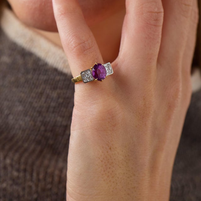 This exceptional vintage ring is centered by a GIA-certified oval cut pinkish purple sapphire weighing 2.65 carats....