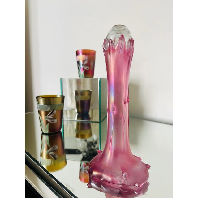 This is not your grandma’s cranberry glass bud vase. This early 20th-century handblown glass piece features a striking,...