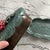 Beautiful handmade butter dish and lid. Colors are turquoise and bronze with a pink flower on top. Has a pattern etched...