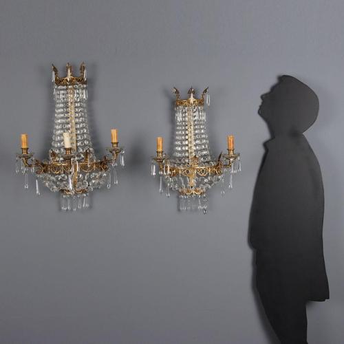 Pair of gilded bronze wall lamps featuring Neoclassical motifs. Clear glass bobeches, necklaces, and pendants. One wall...