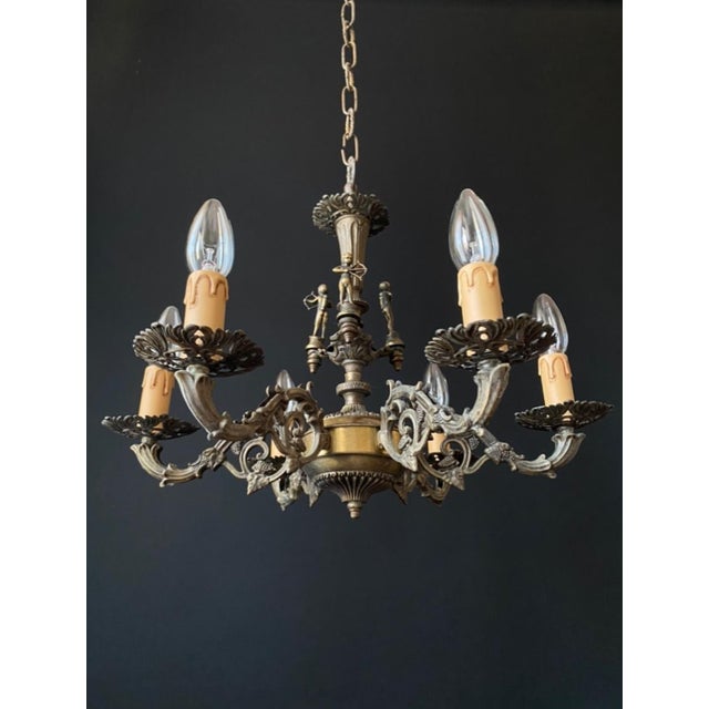 The chandelier is made of brass. It is adorned with bronze elements. Magnificent artistic wrought ironwork! the chandelier...