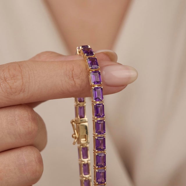 Wrap your wrist in deep, regal purple tones with this captivating tennis bracelet. Highlighting brilliant step-cut stones...