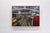 This oil on wood panel artwork captures the interior of a dollar store, depicting a cashier amidst aisles filled with...
