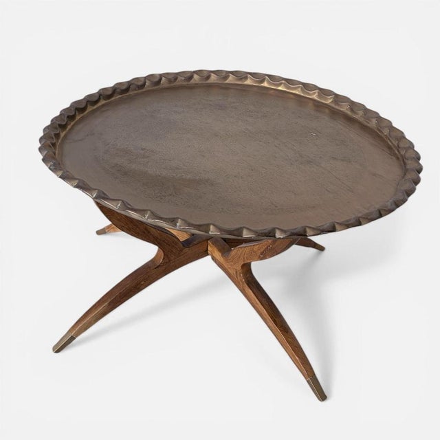 A striking mid century teak and brass coffee table, featuring an elegant spider-leg base and a sculptural circular form....