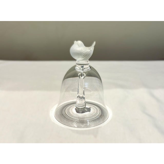 This elegant Lalique crystal table bell features a delicately modeled frosted sparrow perched atop the handle, a graceful...