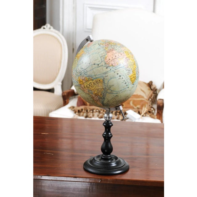A small French terrestrial globe from the 20th century, with metal protractor and circular black wooden base. Created in...