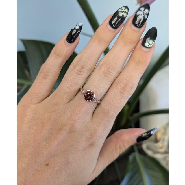A natural red spinel sits at the center of this solid 14K yellow gold ring, flanked by two pink sapphire side stones. Both...