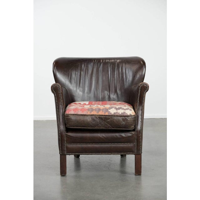 This lovely, subtle dark brown armchair made of cowhide leather with a reversible Kelim seat cushion. This lovely dark...