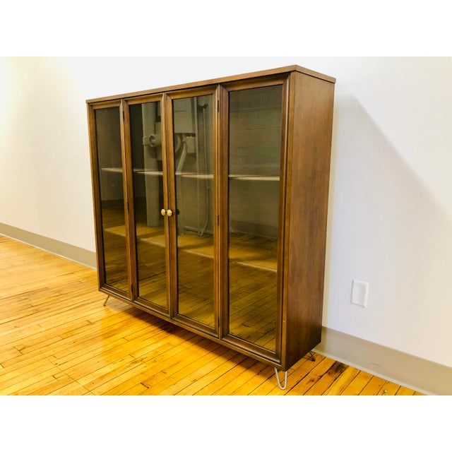 A lovely Broyhill Brasilia display cabinet/shelving unit atop custom metal hairpin legs. This piece features a pair of...
