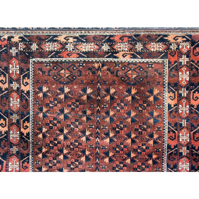 A beautiful early 20th century Persian Baluch rug with an all-over stylized flower pattern woven in red, orange, and black...