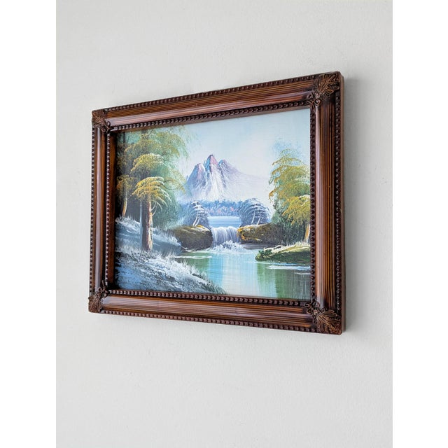 A framed Mid Century oil painting depicting a mountain-capped waterfall and lush nature scene, unsigned. Dimensions:...