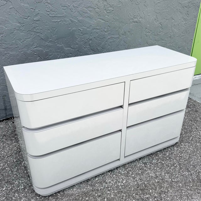 A sleek embodiment of postmodern design, this dresser features a smooth gray high-gloss laminate finish paired with softly...