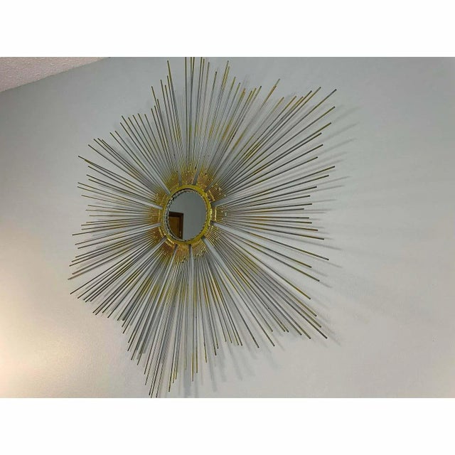 A stunning vintage gilded metal Sunburst Mirror in the style of Chaty Vallauris from c. Mid 20th Century. The central...