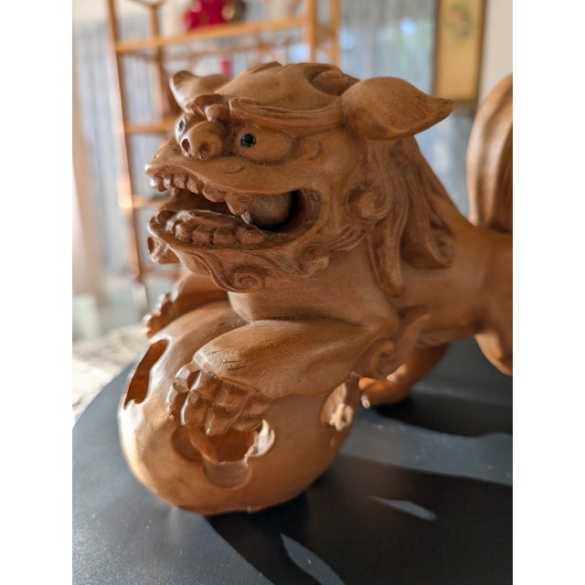 A powerful vintage hand-carved Foo Dog sculpture, facing-left crafted from solid wood and rich with symbolic detail. This...