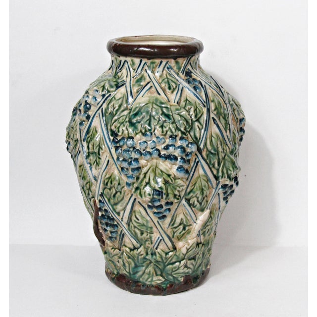A wonderfully textured vintage pottery vase with raised grape clusters, curling vines, and a trellis motif, finished in...