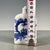 This is a charming vintage porcelain snuff bottle, decorated in the classic blue and white palette. The bottle features a...