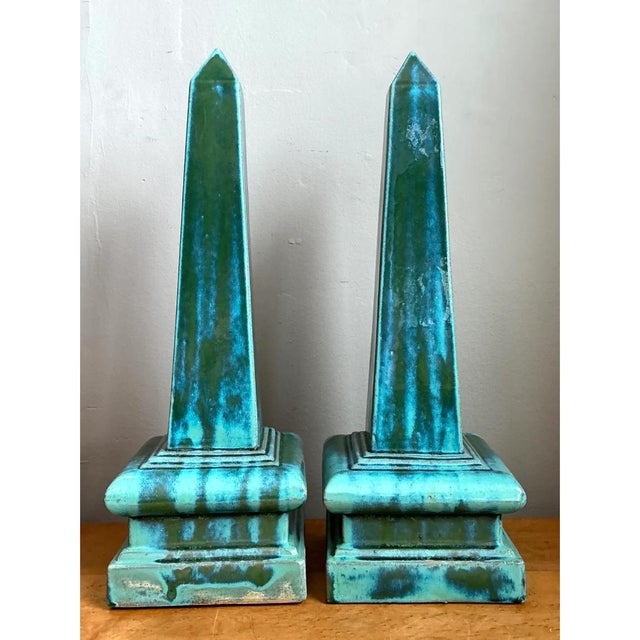 This pair of obelisks presents a classic architectural silhouette, each tall, four-sided shaft tapering gradually from a...