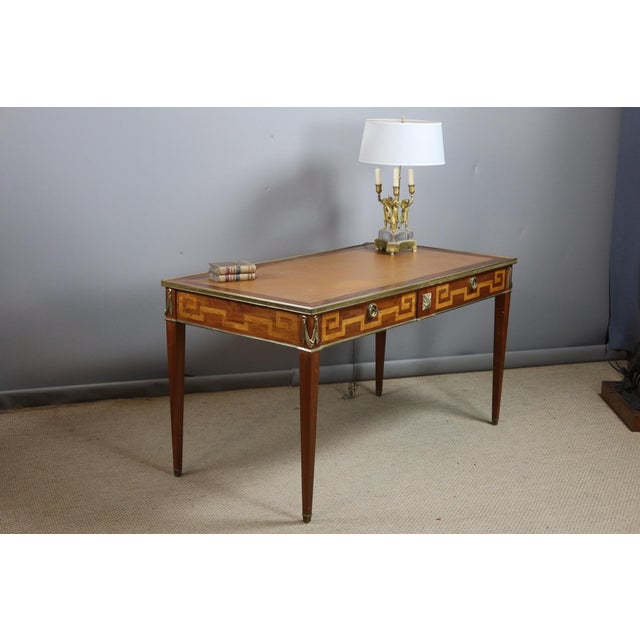 A Directoire-style marquetry desk resting on four tapered legs ending in bronze sabots. It features two drawers in the...