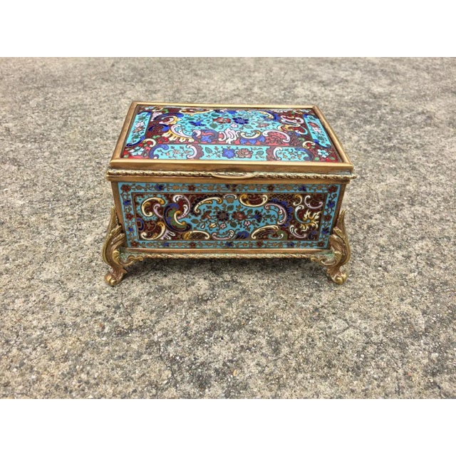 The lovely jewel casket has five champlevé enamel panels each with floral and scrolling decoration on a turquoise ruby...