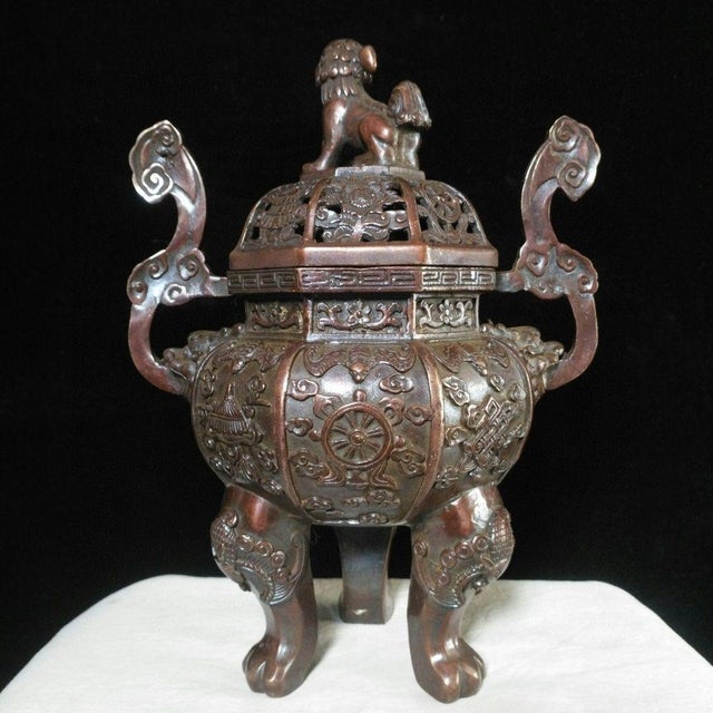 This striking vintage bronze incense burner, or censer, features a rounded body supported by three curved legs and flanked...