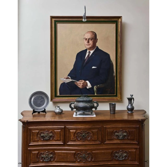 A representative portrait of a middle-aged man, painted in oil on canvas. The sitter is dressed in a dark suit with a tie...