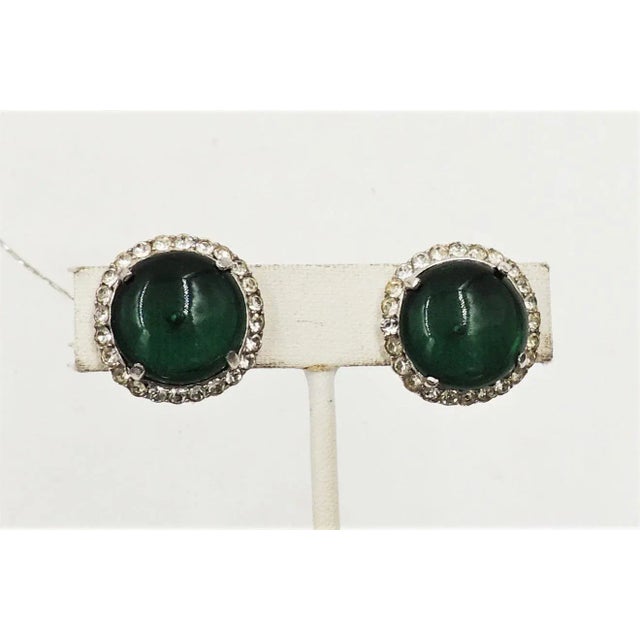 This is part of Chairish’s Costume Jewelry assortment. Circa early 1950s round rhodium plated cabochon faux-emerald and...