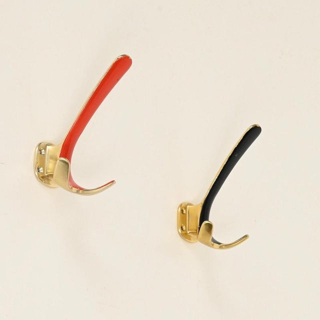 Wonderful and unique set of four Mid-Century coat hooks entirely crafted from solid brass and enriched with black and...