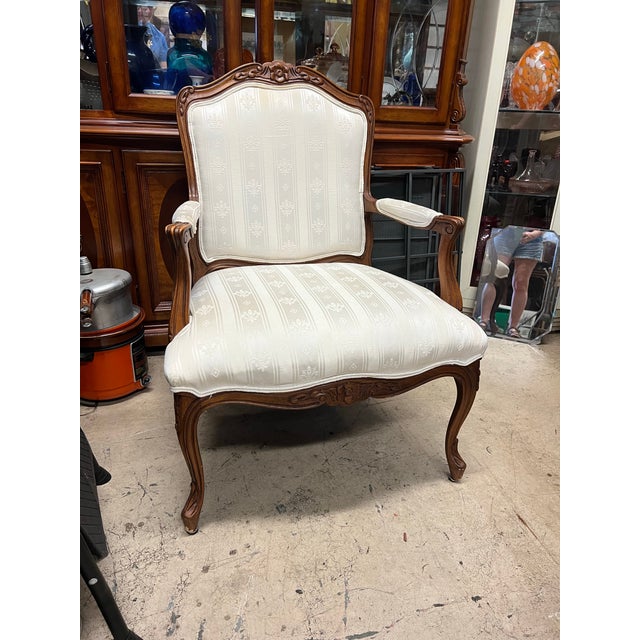 French Provincial Louis XV design with striped fabric upholstery and carved walnut wood. This piece features a classic...