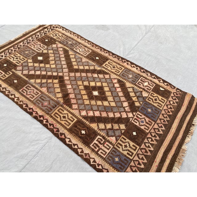 A small handwoven Maimana kilim from northern Afghanistan, worked on a deep chocolate ground with camel, slate blue,...