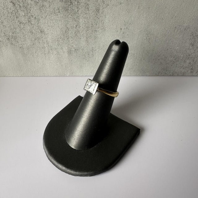 Indulge in the artistry and elegance of this Handcrafted 18kt Two Tone Tension Set Princess Cut Diamond Solitaire...