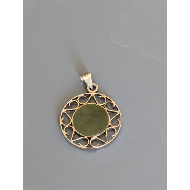 Medium, small, a classy silver Chai inserted in Jade with a surrounded by stylized filigree.