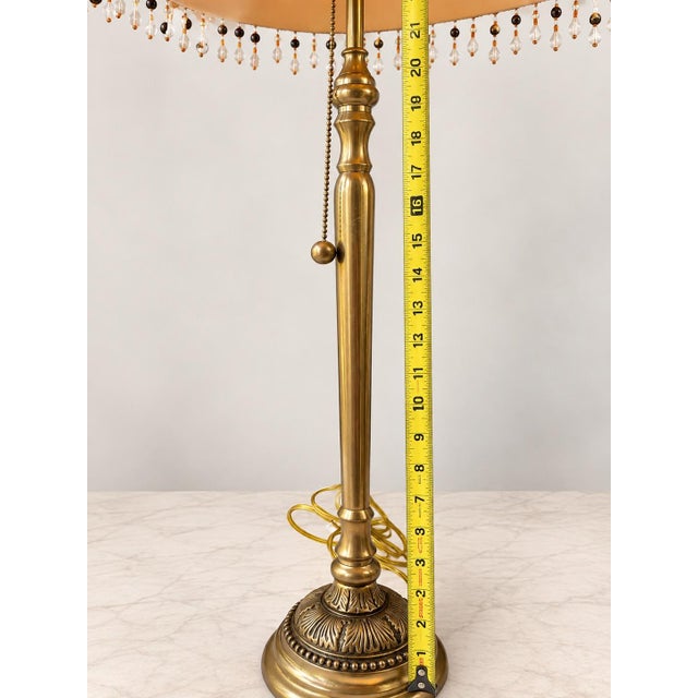 Elegant vintage table lamp featuring a richly detailed brass-tone metal base with an ornate decorative foot and turned...