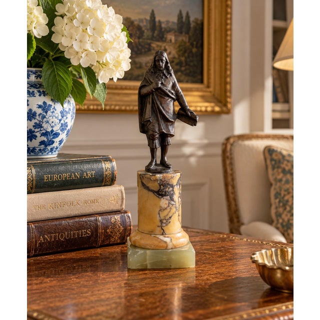 A Grand Tour–style classical figure in brass, mounted on a cylindrical marble base. The slightly more relaxed posture and...