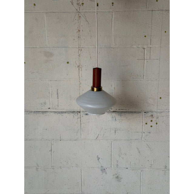 This elegant ceiling pendant light features a flying-saucer-shaped opaline glass shade that casts a soft, ambient glow. A...