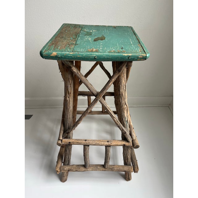 This Adirondack table showcases the artistry of folk craftsmanship. Its twig peeling bark frame supports a weathered blue...