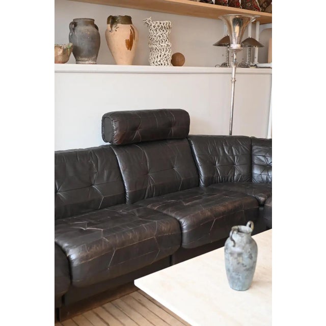 A Swiss black leather modular sofa in the style of De Sede. Two end sections, a corner and three side sections (two with...