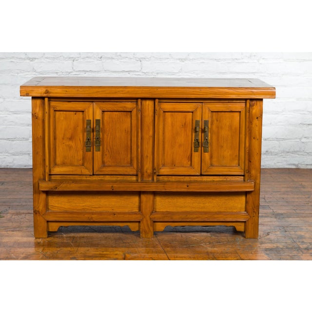 An antique Chinese wooden console cabinet from the early 20th century, with four doors, inner shelves, removable...