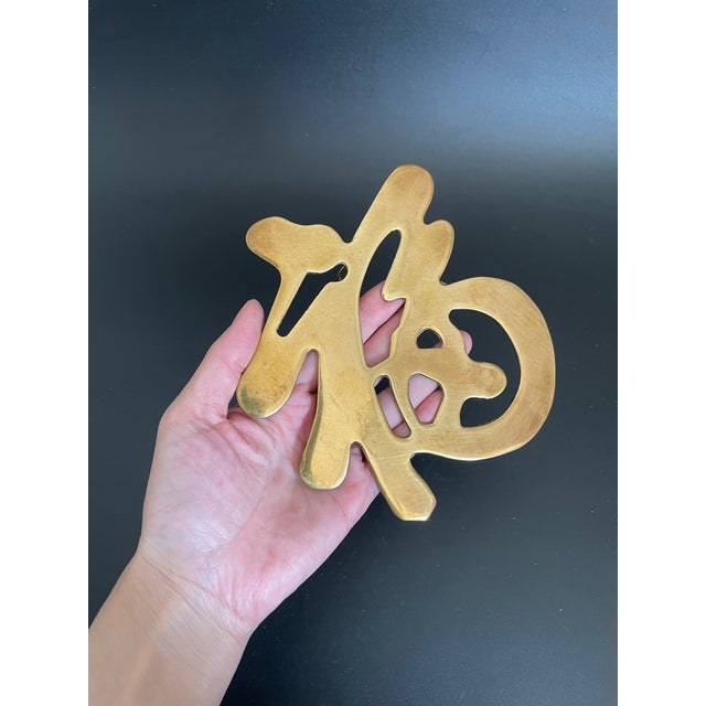 A vintage brass trivet in the form of the Chinese Fortune symbol, representing good luck, happiness, prosperity, and...