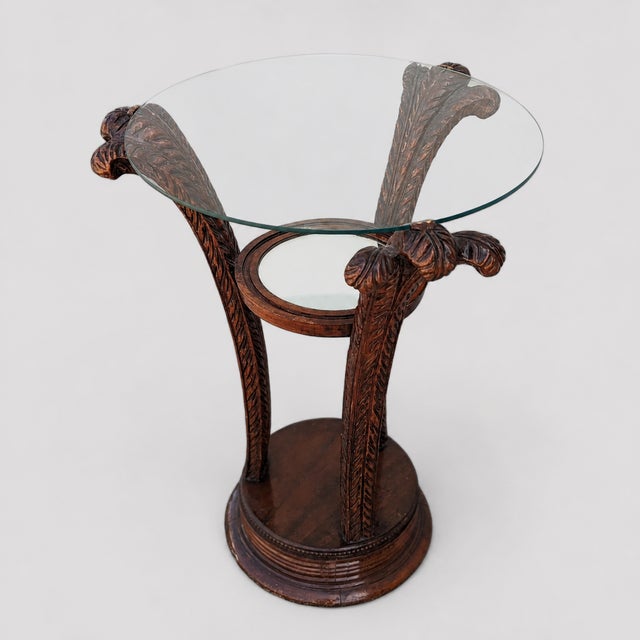 An early 20th-century Art Nouveau side table with a circular glass top, carved wood pedestal base, and a smaller round...