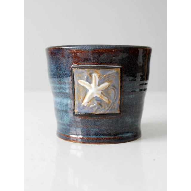 This vintage studio pottery cachepot vase is a hand-crafted ceramic piece featuring a striking central starfish motif....