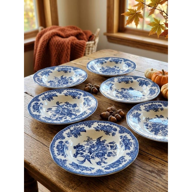 This refined set of six rimmed deep plates displays one of the most iconic English ceramic designs. The central scene...