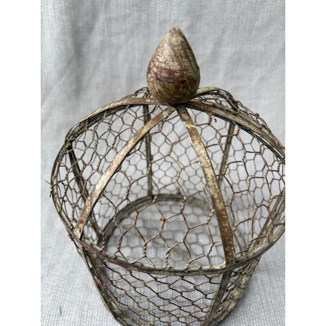 Small vintage chicken wire indoor birdcage or garden cloche with a pointed bud shaped finial. The base opens as a door...