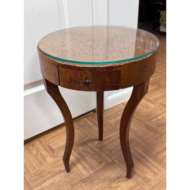 A petite Italian style side table with a richly figured burl wood top over a walnut-veneered drum apron. A single bow-...