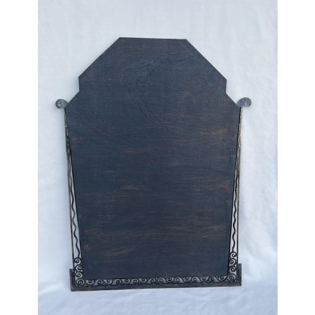 Large mirror to be installed, from Art Deco to 1930, in hammered and patinated wrought iron, decorated with winding and...